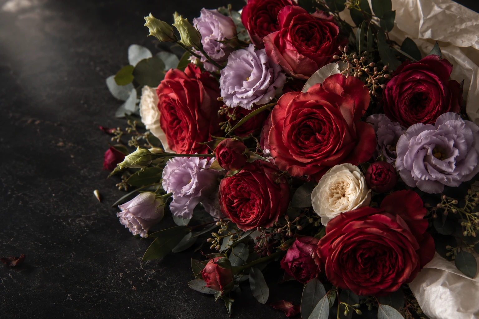 Illustrative bouquet of red, pink, lilac and cream blooms against a dark background; not a photograph from Flowers By Bernadette.